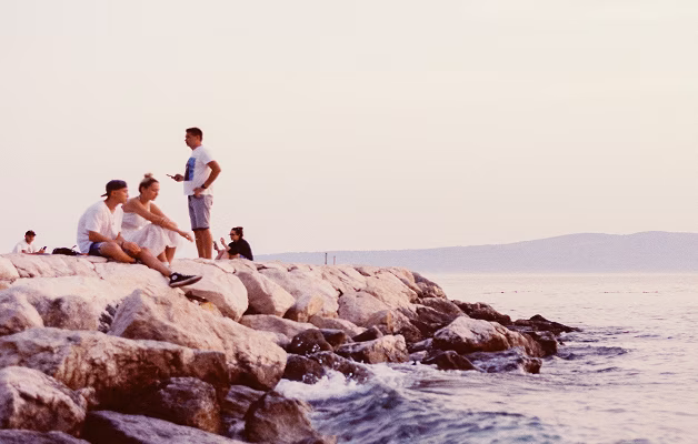 People relaxing on coastal rocks overlooking the sea